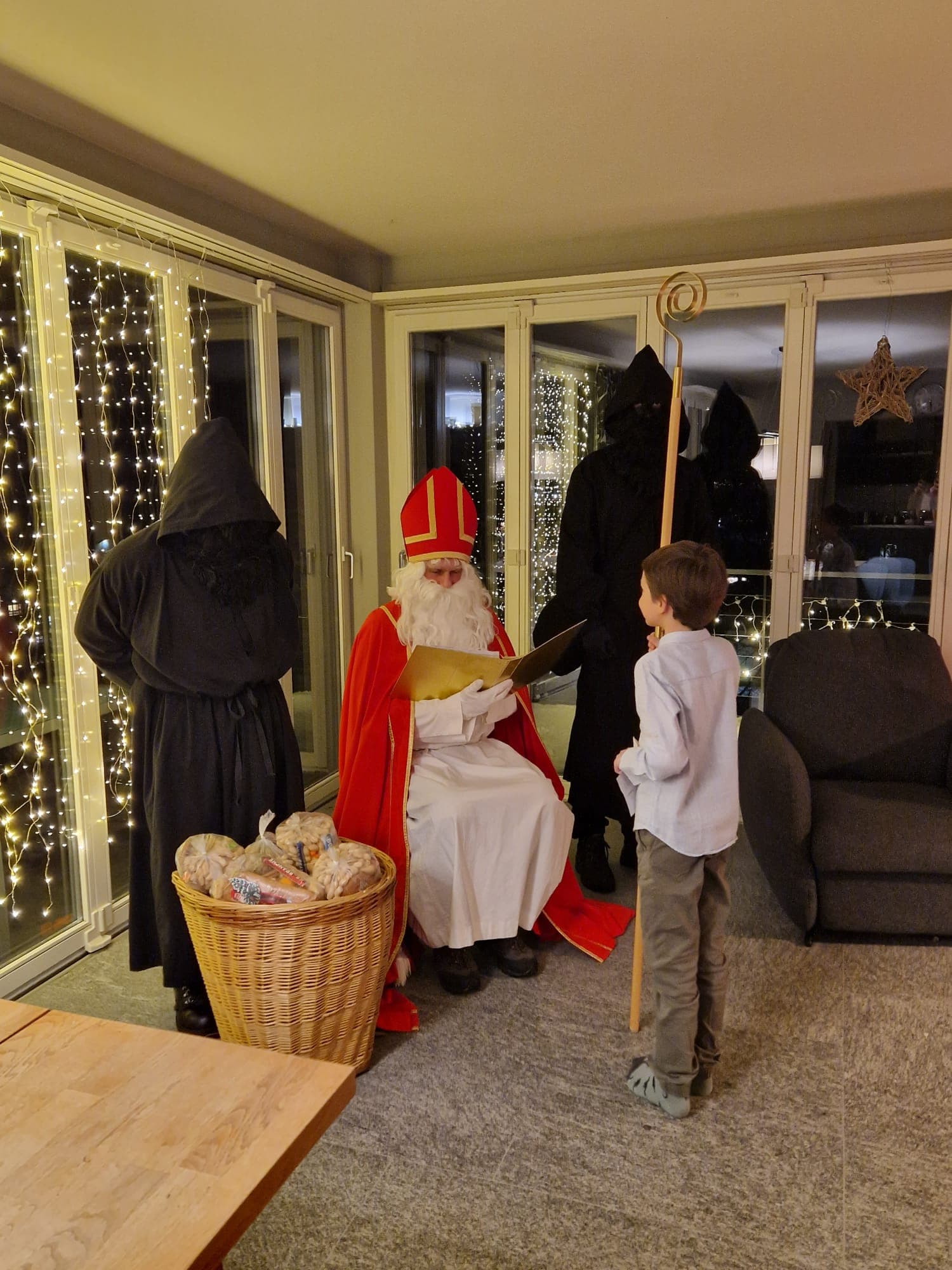 Samichlaus-Besuch in einer Stube mit Lichterdekoration